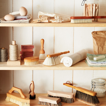 Artisan hands crafting a natural Redecker brush with wooden handle and black bristles on a workbench