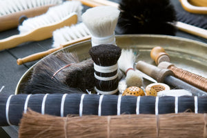 Brushes with natural bristles made with horsehair, goat hair, and plant fibers arranged in a workshop tray