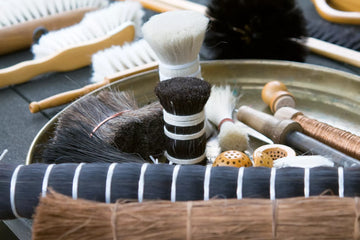 Brushes with natural bristles made with horsehair, goat hair, and plant fibers arranged in a workshop tray