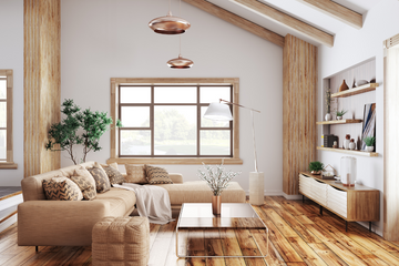 Sunlit neutral living room with tan sectional, patterned pillows, wood floors, and modern pendants—calm, natural materials.