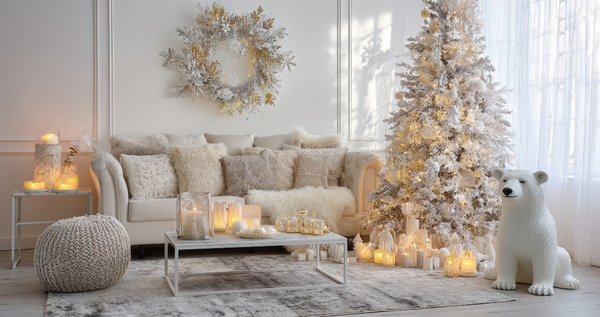 Bright living room with neutral sofa, white Christmas tree, candles, and wreath—cozy winter décor scene.